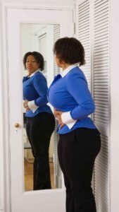 Confident woman looking in mirror, symbolizing reclaiming self-worth. 